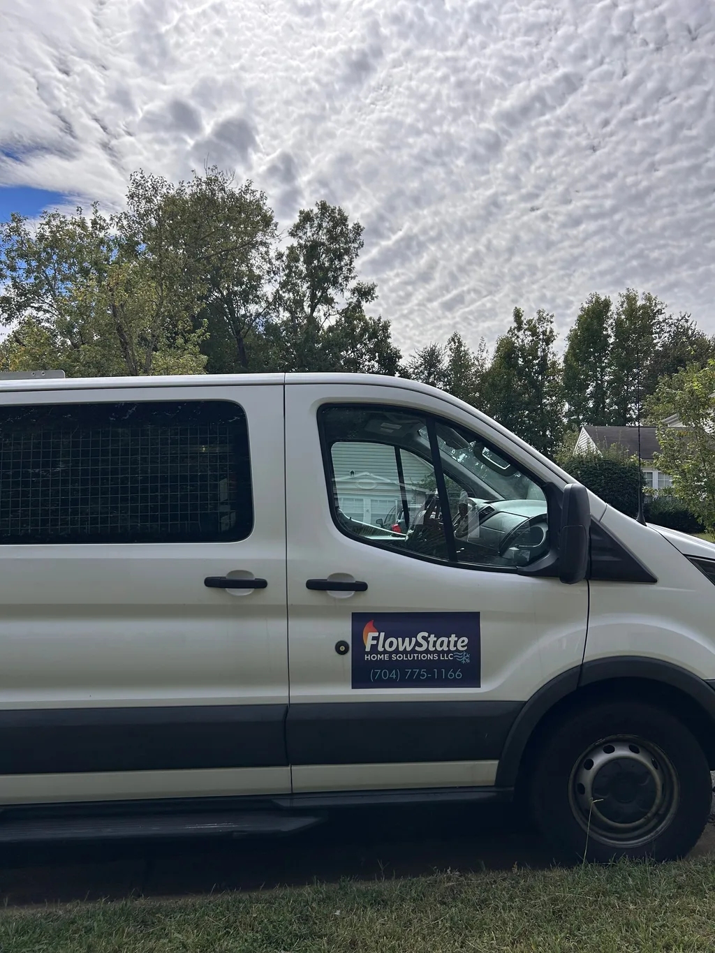 White FlowState Home Solutions work van parked on grass with the door decal and phone number visible